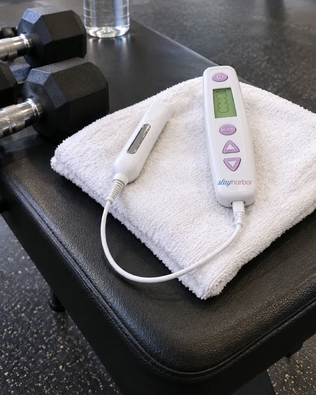 The trainer controller and probe on a towel on a gym bench next to dumbbells